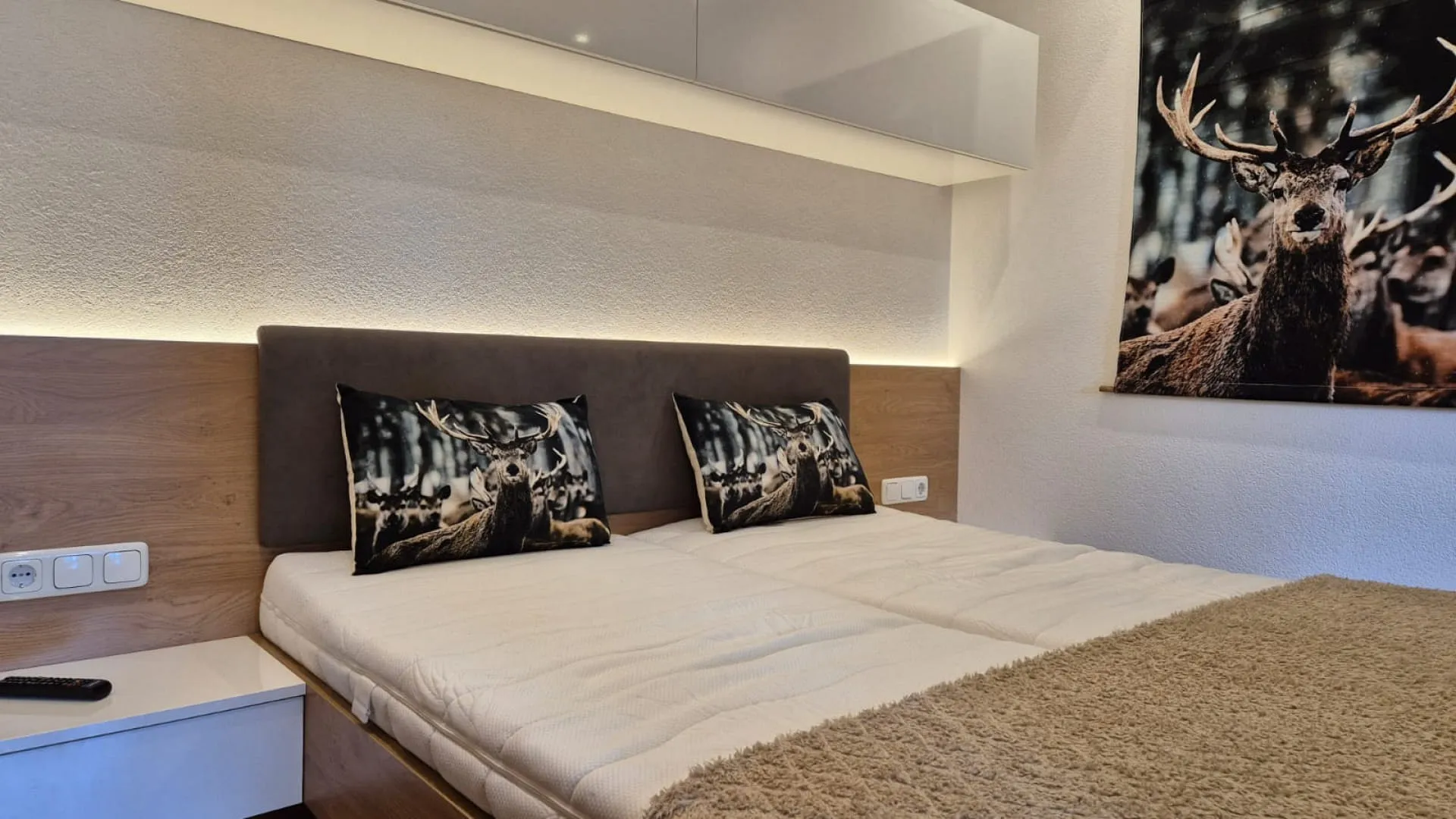 Bedroom with a bed and pillows, wall decor featuring a deer