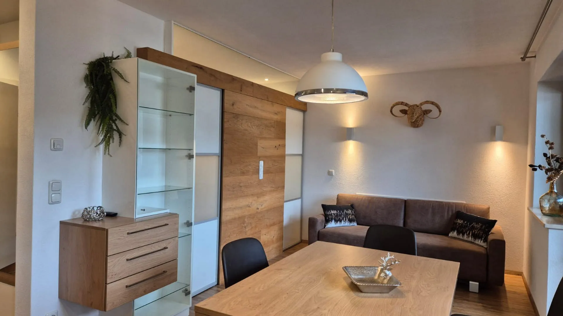 Modern living room with sofa, dining table, and wooden shelf.
